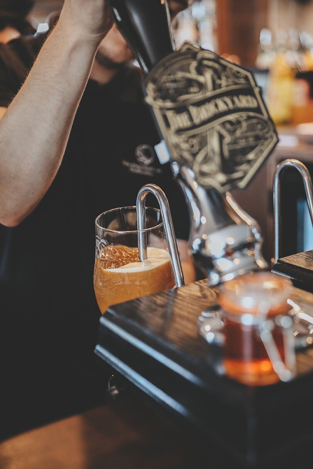 A tap with a beer logo and a glass of beer on a bar counter.