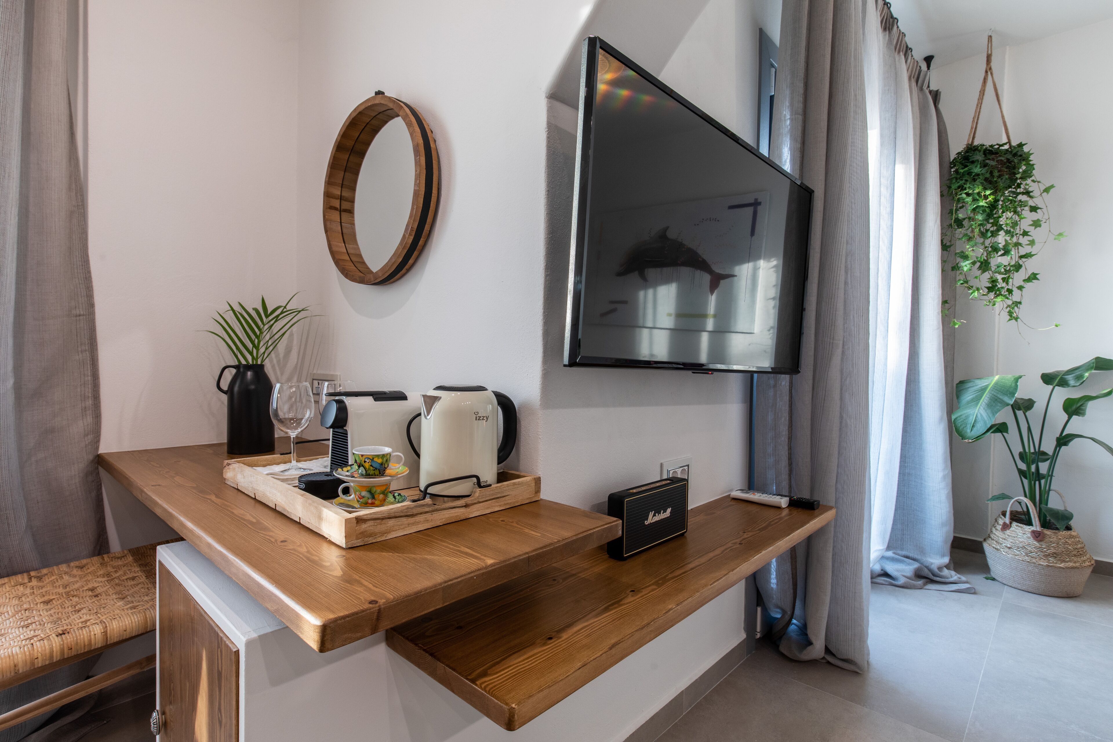 Un salon moderne avec une table basse en bois, un téléviseur à écran plat, une machine à café, une bouilloire et un haut-parleur.