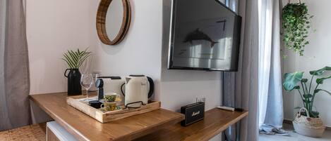 Un salon moderne avec une table basse en bois, un téléviseur à écran plat, une machine à café, une bouilloire et un haut-parleur.
