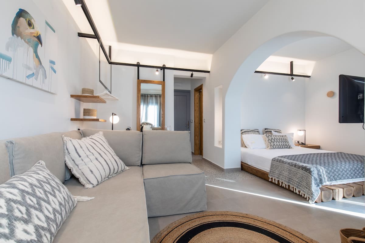 Un dormitorio moderno con sofá, cama y un espejo grande.