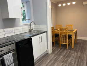 Uma cozinha moderna com armários brancos, lava-louças pretas e bancada de granito.