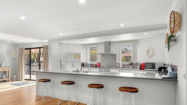 Una cocina moderna con una isla grande, taburetes de bar y vistas al exterior.