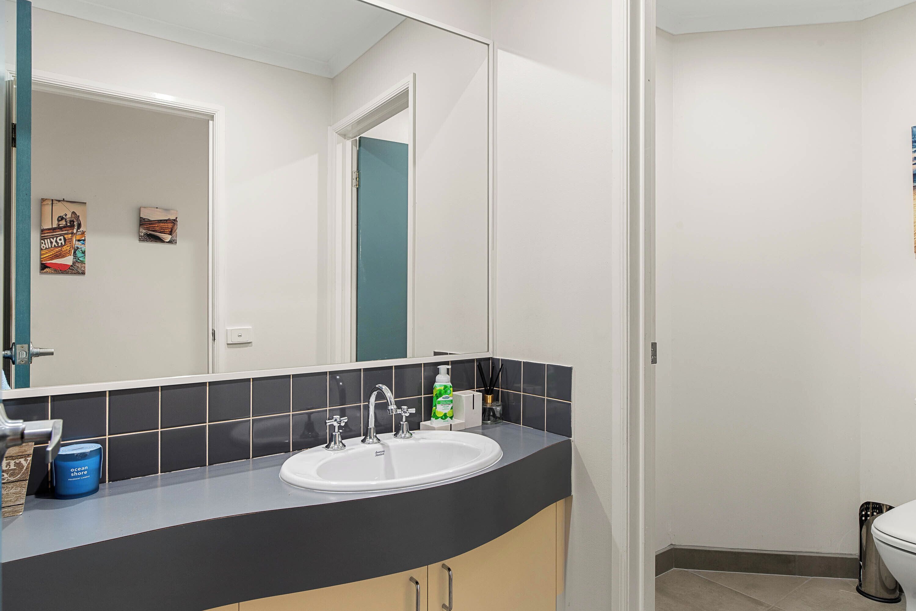 A modern bathroom with a white sink, black countertop, and a large mirror.