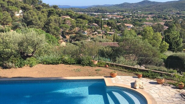 A pool with a clear view of a hillside landscape, including houses and trees. - Maison en Pierres Avec vue sur mer et les Îles (Bormes-les-Mimosas)