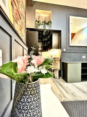 Een modern interieur met een vaas met bloemen op een tafel, een spiegel en een plank met flessen.