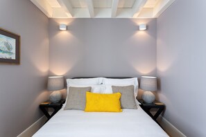 Une chambre à coucher avec un lit, deux tables de chevet avec des lampes et un tableau encadré au mur.