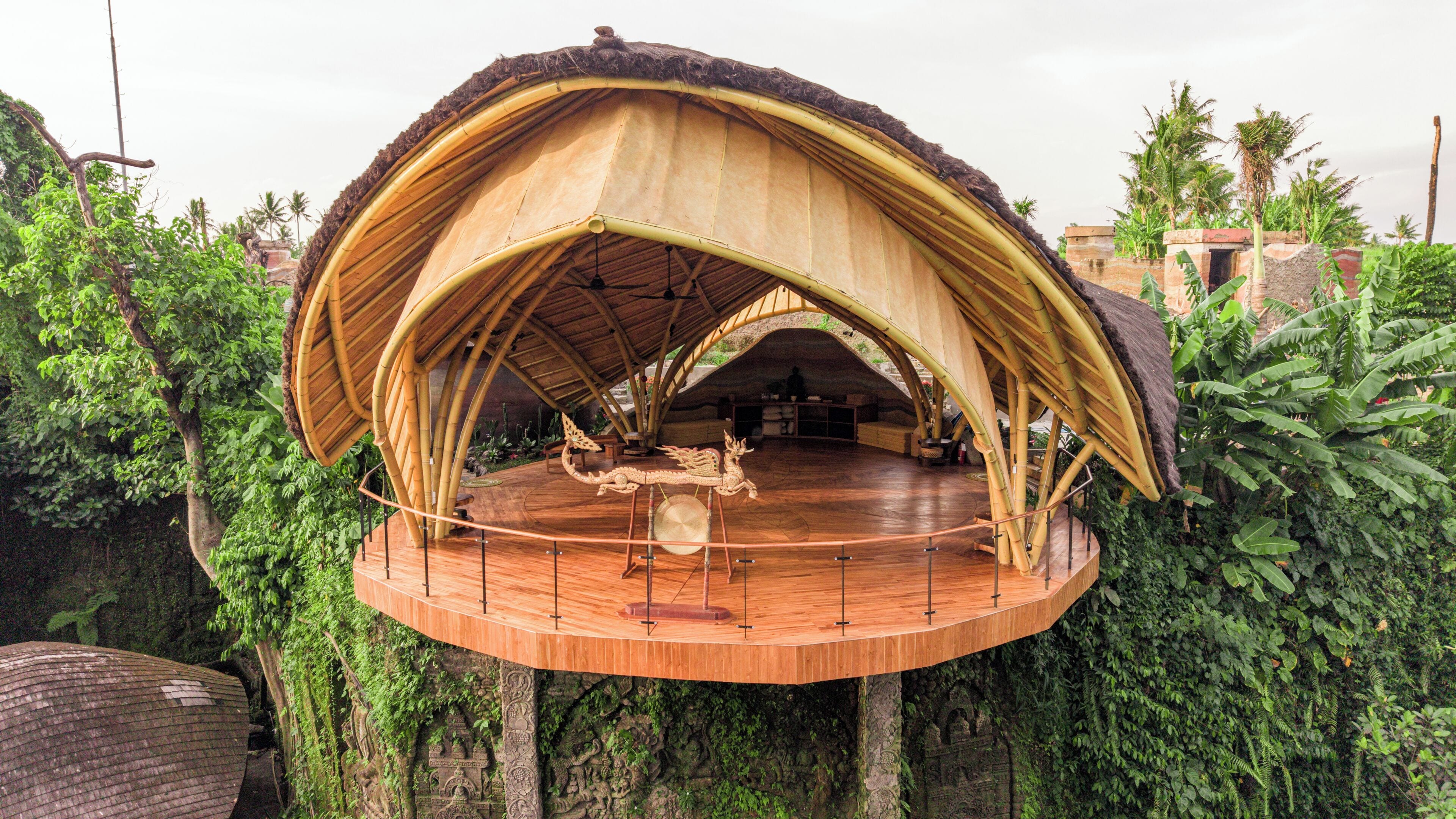 A circular wooden stage with a thatched roof, surrounded by lush greenery.