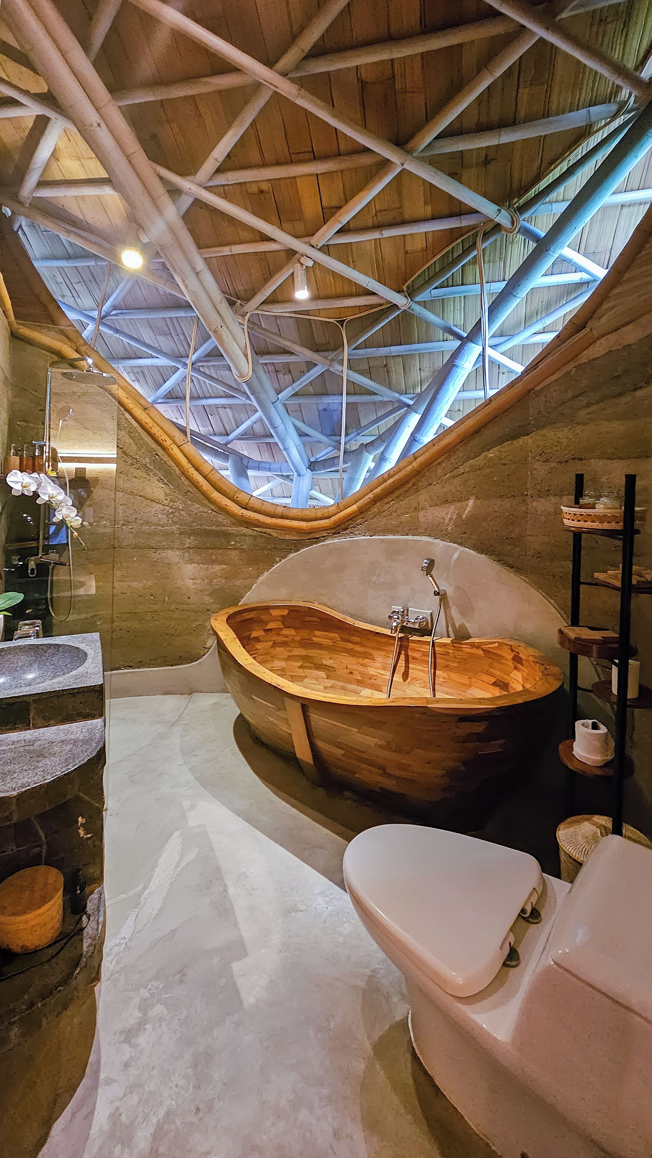 A unique bathroom with a large wooden bathtub, a separate toilet, and a skylight ceiling.