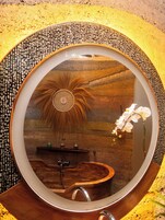 Un baño con un espejo redondo, una bañera de madera y un lavabo.