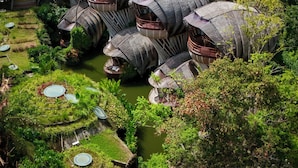 A cluster of unique, dome-shaped buildings with balconies, surrounded by lush greenery and a small water body. -  Ulaman Eco Luxury Resort (Tabanan)