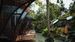 A circular wooden platform with a netted edge, surrounded by a lush garden and a water channel. -  Ulaman Eco Luxury Resort (Tabanan)