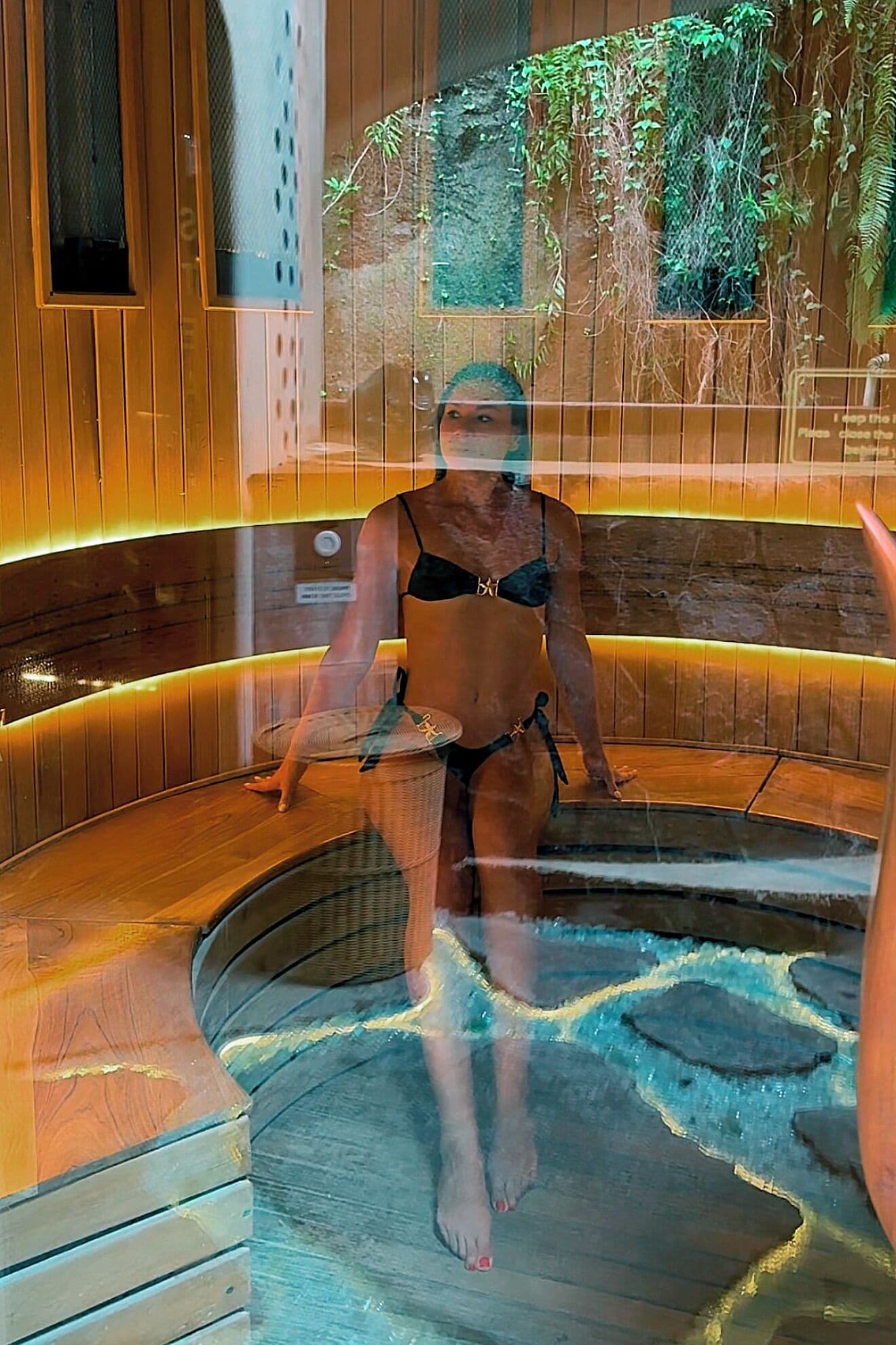 A person in a spa setting with a wooden interior and a water feature.