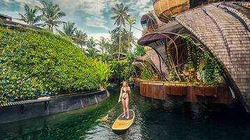 Una persona haciendo paddleboard en un canal con un edificio moderno a un lado.