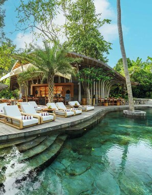 A resort with a pool, lounge chairs, and a bar area. - Ulaman Eco Luxury Resort - Adults Only (Tabanan)