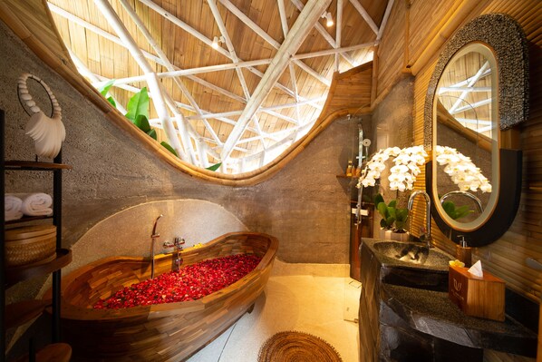 A wooden bathtub filled with red flowers, a wooden vanity with a mirror, and a ceiling with a geometric wooden design. - Ulaman Eco Luxury Resort - Adults Only (Tabanan)