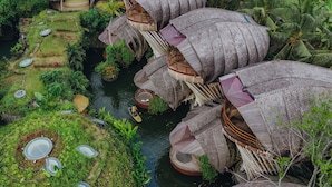 A unique floating house structure with multiple levels, surrounded by lush greenery and a water body. -  Ulaman Eco Luxury Resort (Tabanan)