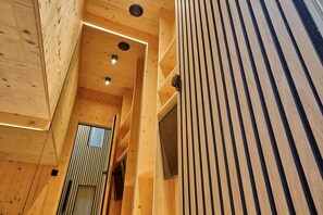 Un intérieur en bois avec un plafond en pente, des étagères intégrées et une porte donnant sur une autre pièce.