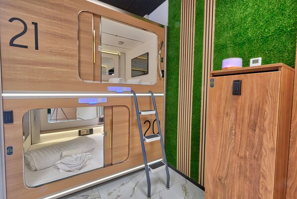 Una cama litera con escalera, un armario de madera y una pared verde.
