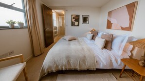 Une chambre à coucher avec un lit, une table de chevet et une fenêtre avec des rideaux.