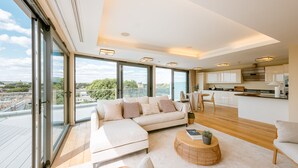 Un salon moderne avec un grand canapé, une table basse et une vue sur la ville grâce à de grandes fenêtres.
