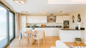 Une cuisine moderne avec des meubles blancs, un îlot central et un coin repas comprenant une table ronde et des chaises.