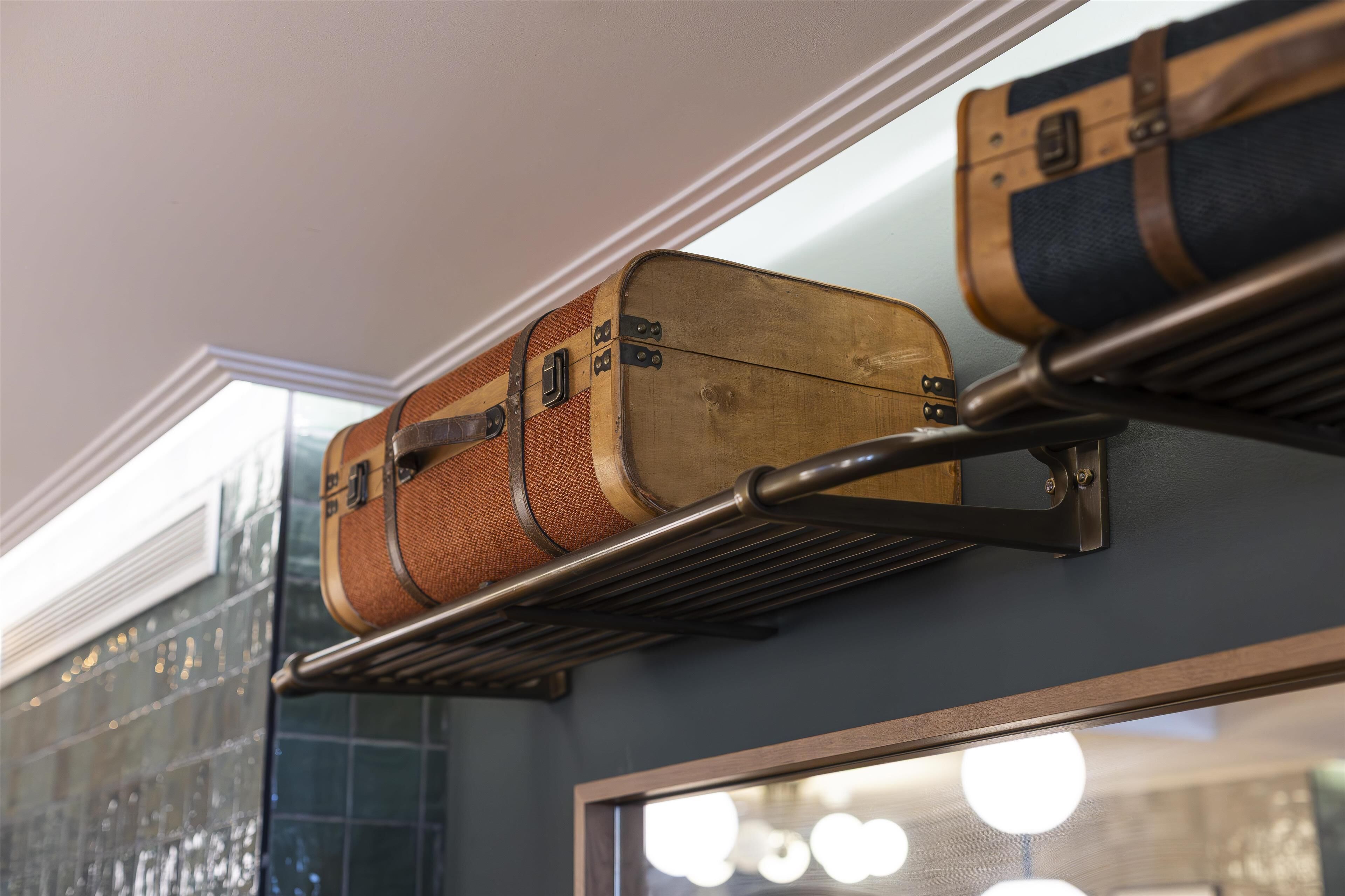 A wall-mounted luggage rack with vintage suitcases.