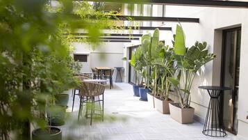 Un patio al aire libre con suelo de madera, plantas en macetas y mobiliario exterior.