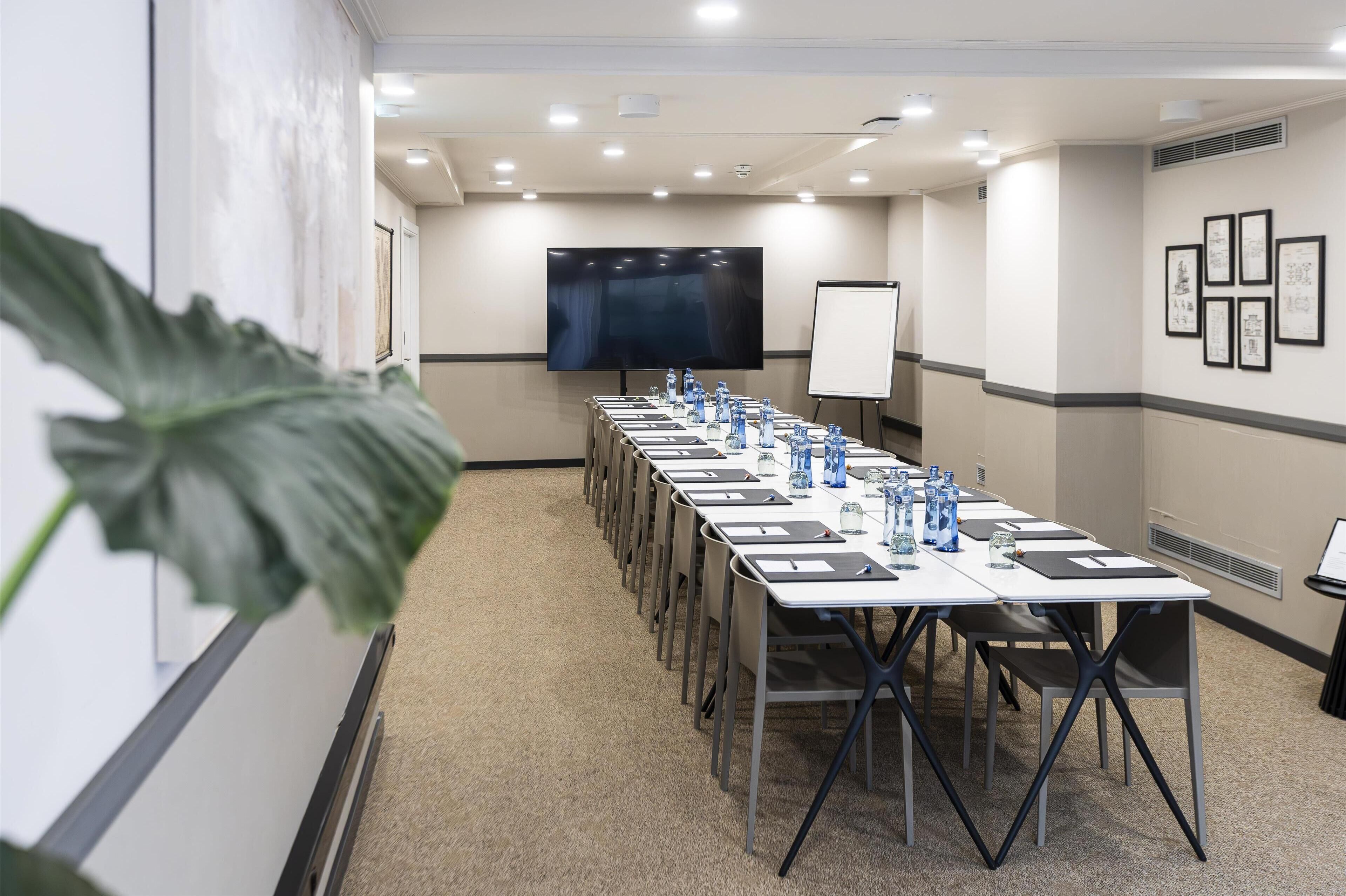 A conference room with a long table, chairs, a projector screen, and a whiteboard.