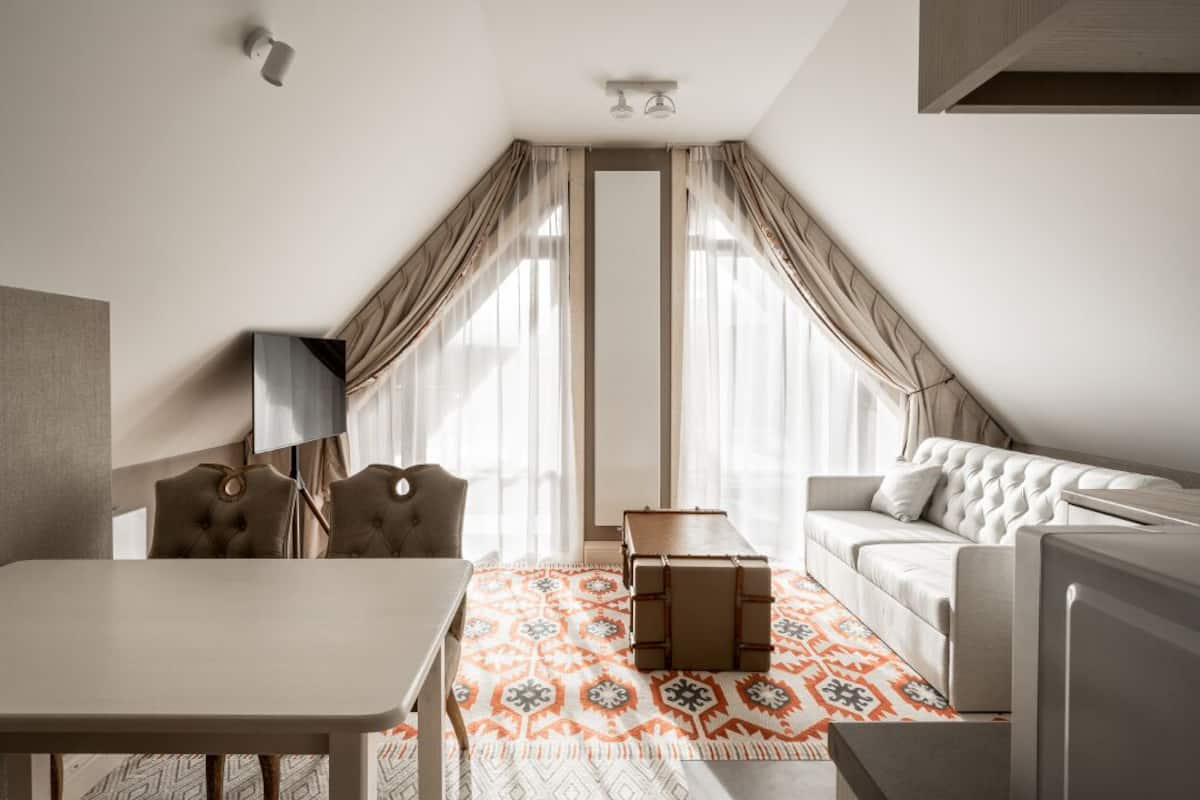 Une chambre d’hôtel moderne comprenant une table à manger, deux chaises, un canapé, une petite table et un tapis décoratif.