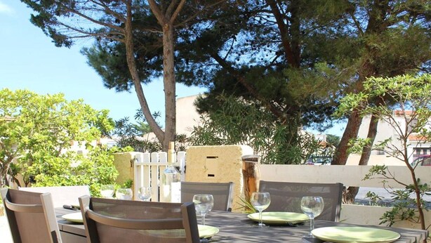 Un'area pranzo all'aperto con un tavolo apparecchiato per quattro persone, circondato da sedie.