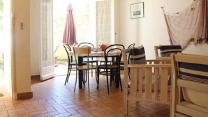 Un'area pranzo con tavolo e sedie, una panca in legno e un'amaca.