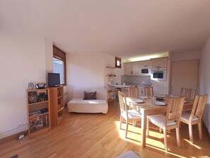 A compact living space with a kitchenette, a dining area, and a seating area with a sofa and chairs.