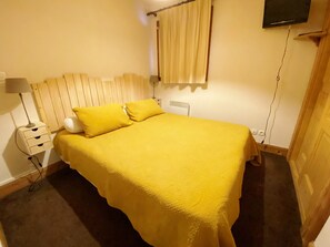 Cozy retreat with a single bed, bedside table, and mounted TV.