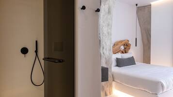 Un dormitorio moderno con cabina de ducha de vidrio, cabecero de madera y mesita de noche.