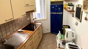 A compact kitchen with beige cabinets, a blue refrigerator, a sink, and a toaster. - Taste of Salt, Capo D'Orlando (Capo d'Orlando)