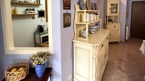 A room with a large mirror, a cream-colored cabinet with decorative plates, and a wicker basket with flowers on a wooden table. - Taste of Salt, Capo D'Orlando (Capo d'Orlando)