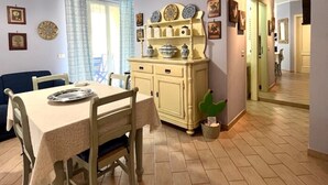 A dining area with a table set for two, a cream-colored cabinet with decorative plates, and a wall clock. - Taste of Salt, Capo D'Orlando (Capo d'Orlando)