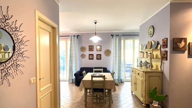 A dining area with a table and chairs, a sofa, and a cabinet with decorative items. - Taste of Salt, Capo D'Orlando (Capo d'Orlando)