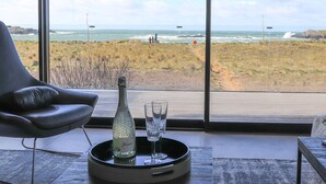 Ein Zimmer mit großem Fenster und Meerblick, eine Champagnerflasche sowie zwei Gläser auf einem Tablett.
