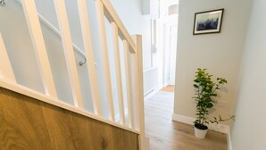 A staircase with wooden steps and white railings leading to a hallway with a potted plant. - 10 Beach Road -  a sea view that sleeps 4 guests  in 2 bedrooms (Menai Bridge)