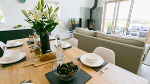 A dining area with a wooden table set for a meal, a bowl of mussels, and a vase of flowers. - Bwncath -  a coastal that sleeps 6 guests  in 3 bedrooms (Llanfairynghornwy)