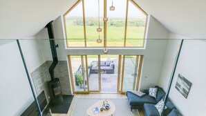 A modern living room with a glass ceiling, a fireplace, a sofa set, and a view of the outdoors. - Bwncath -  a coastal that sleeps 6 guests  in 3 bedrooms (Llanfairynghornwy)