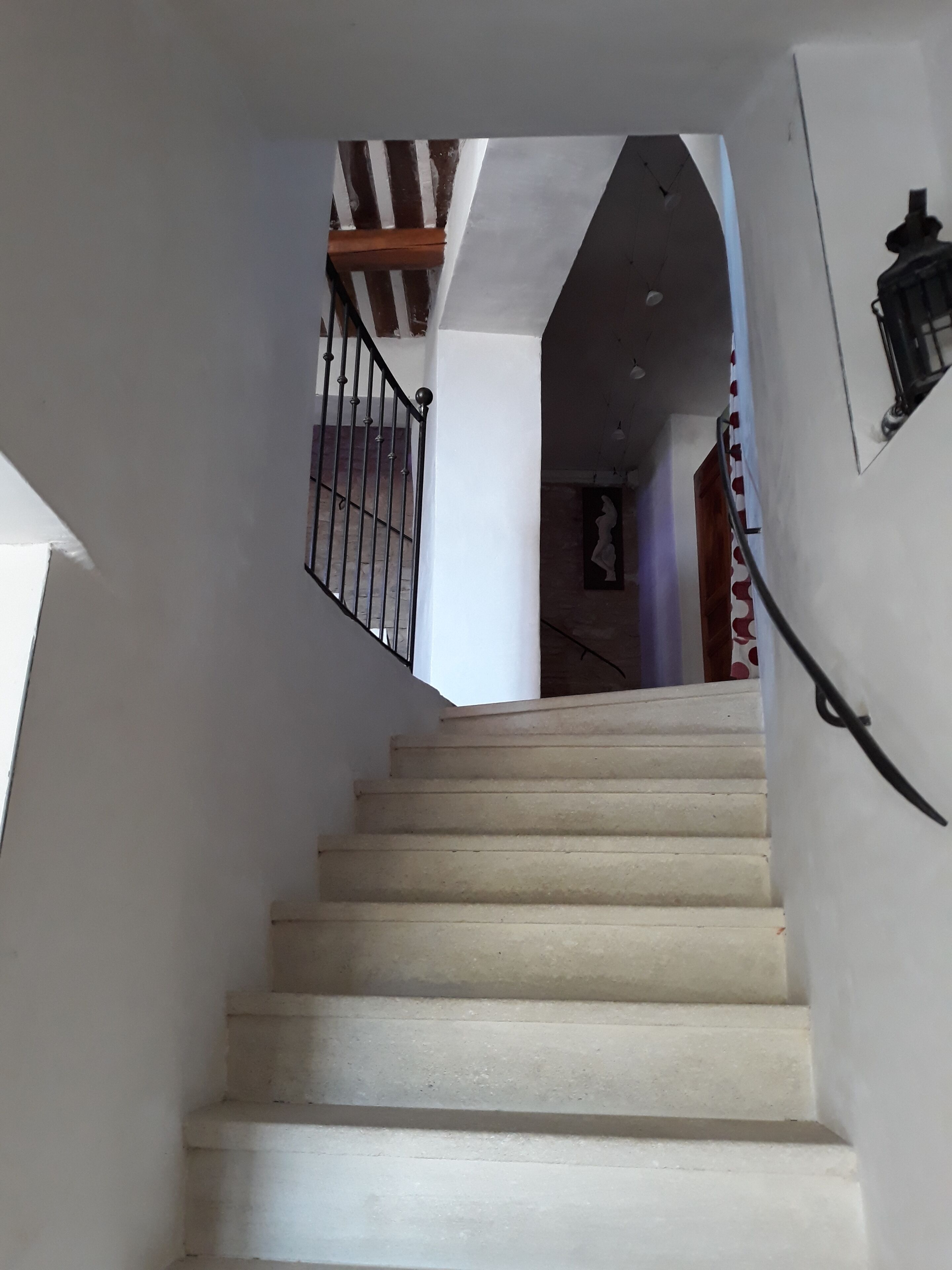 Una escalera con paredes blancas y barandilla negra.