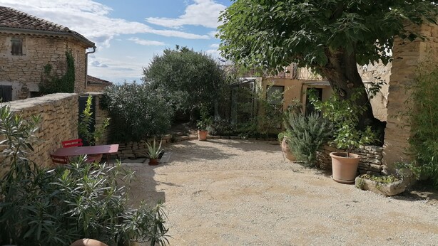 A courtyard with stone walls, potted plants, and a gravel path. - Chambre Dans Maison de Caractère Proche du Mt Ventoux (Crillon-le-Brave)