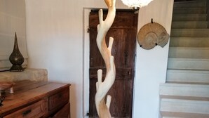A wooden sculpture in a foyer, a wooden cabinet, a door, and a staircase. - Chambre Dans Maison de Caractère Proche du Mt Ventoux (Crillon-le-Brave)