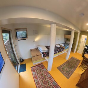 Una habitación compacta con una cama, una mesita, una silla, un televisor y una ventana.