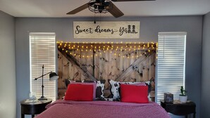 A bedroom with a checkered bedspread, a wooden headboard with string lights, a ceiling fan, and a wall sign that reads "Sweet dreams y'all". - Paradise in the country w/Pool & hot tub! Unplug & Recharge. Pet friendly (Decatur)
