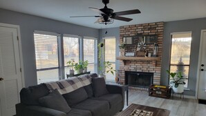 A living room with a gray sofa, a wooden coffee table, and a brick fireplace. - Paradise in the country w/Pool & hot tub! Unplug & Recharge. Pet friendly (Decatur)