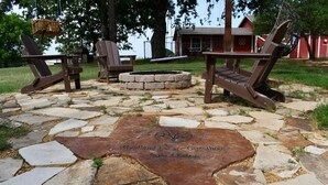 A stone patio with Adirondack chairs and a fire pit, surrounded by a stone wall and trees. - Paradise in the country w/Pool & hot tub! Unplug & Recharge. Pet friendly (Decatur)