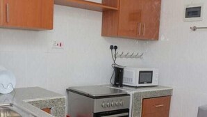 A compact kitchen with a microwave, oven, and stainless steel sink.